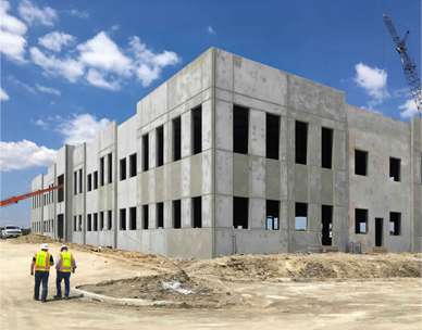 Commerical building in construction with two workers walking in front